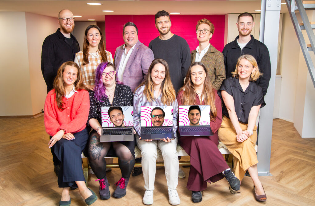 The Podcast Guys team at their London branded podcast agency HQ, with remote team members joining on laptop screens